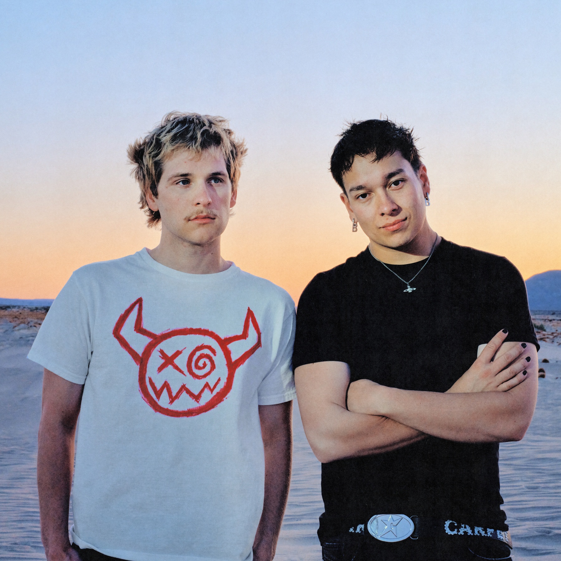 Two guys next to eachother standing for a sunset