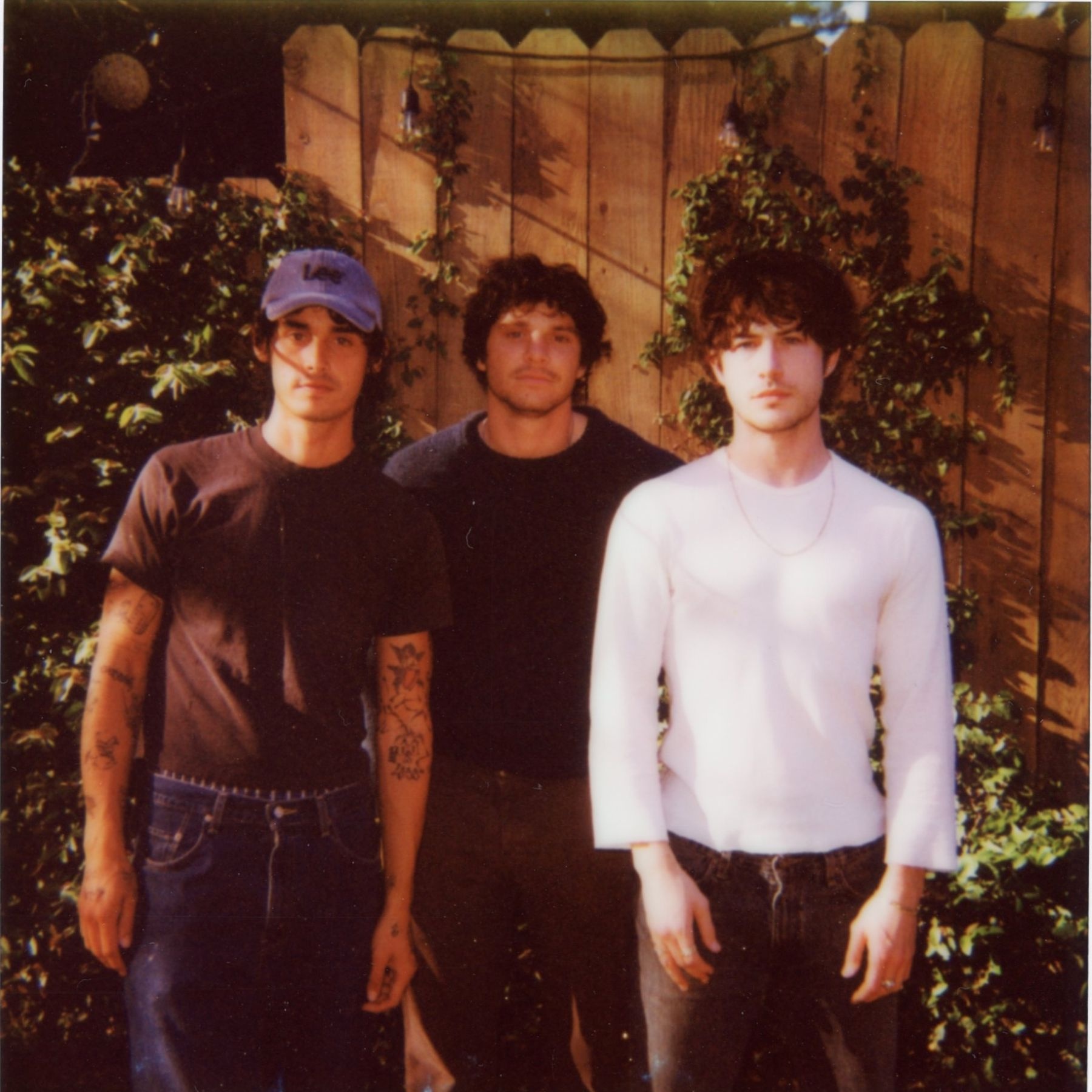Three men standing in front of a fence