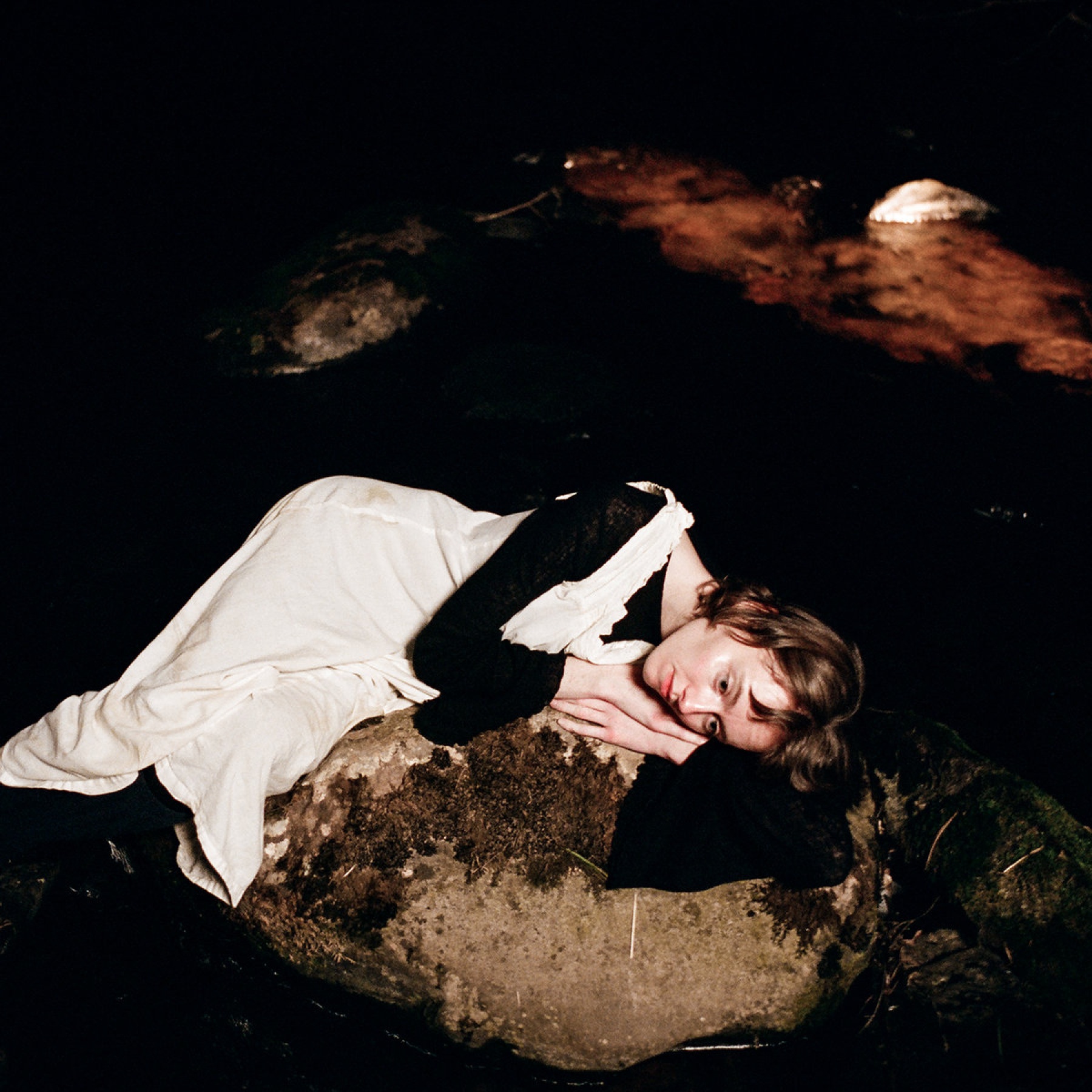 Woman lying on a stone on her side