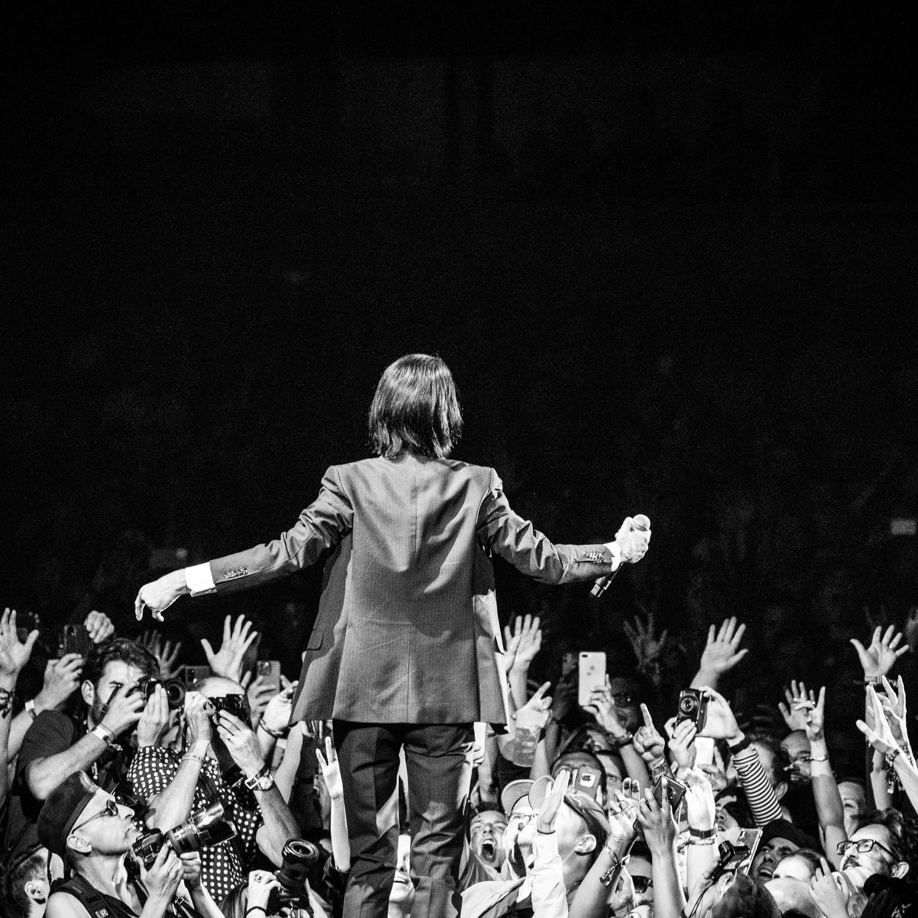 Man singing on stage, black and white within crowd