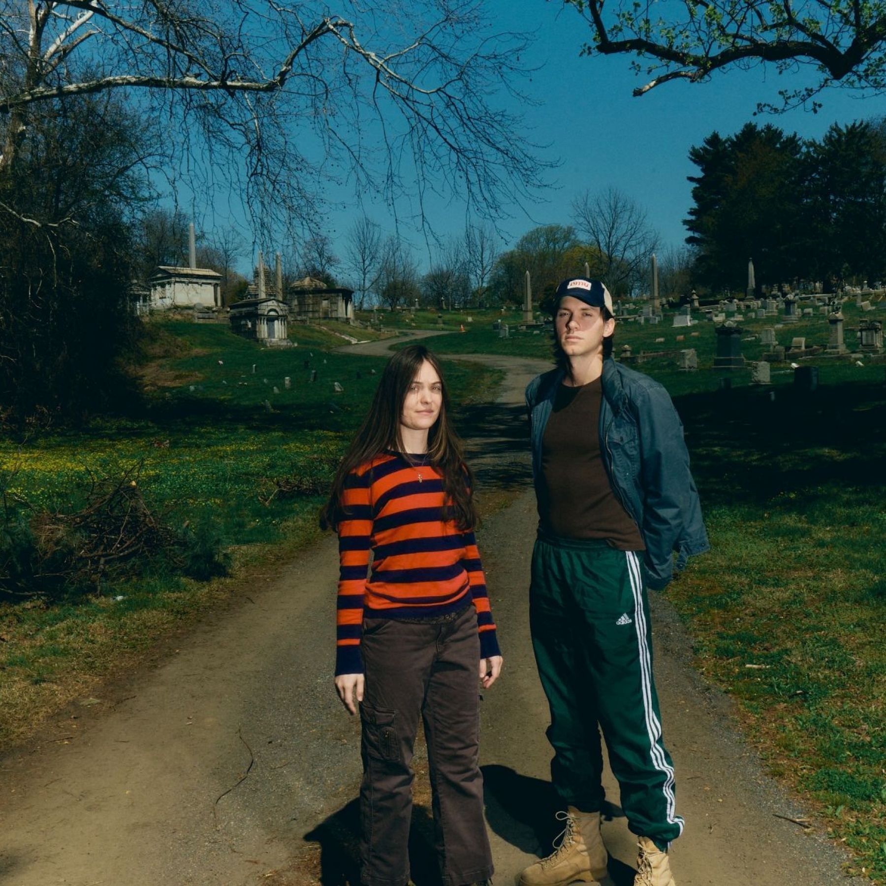 Two people standing in a sunny graveyard
