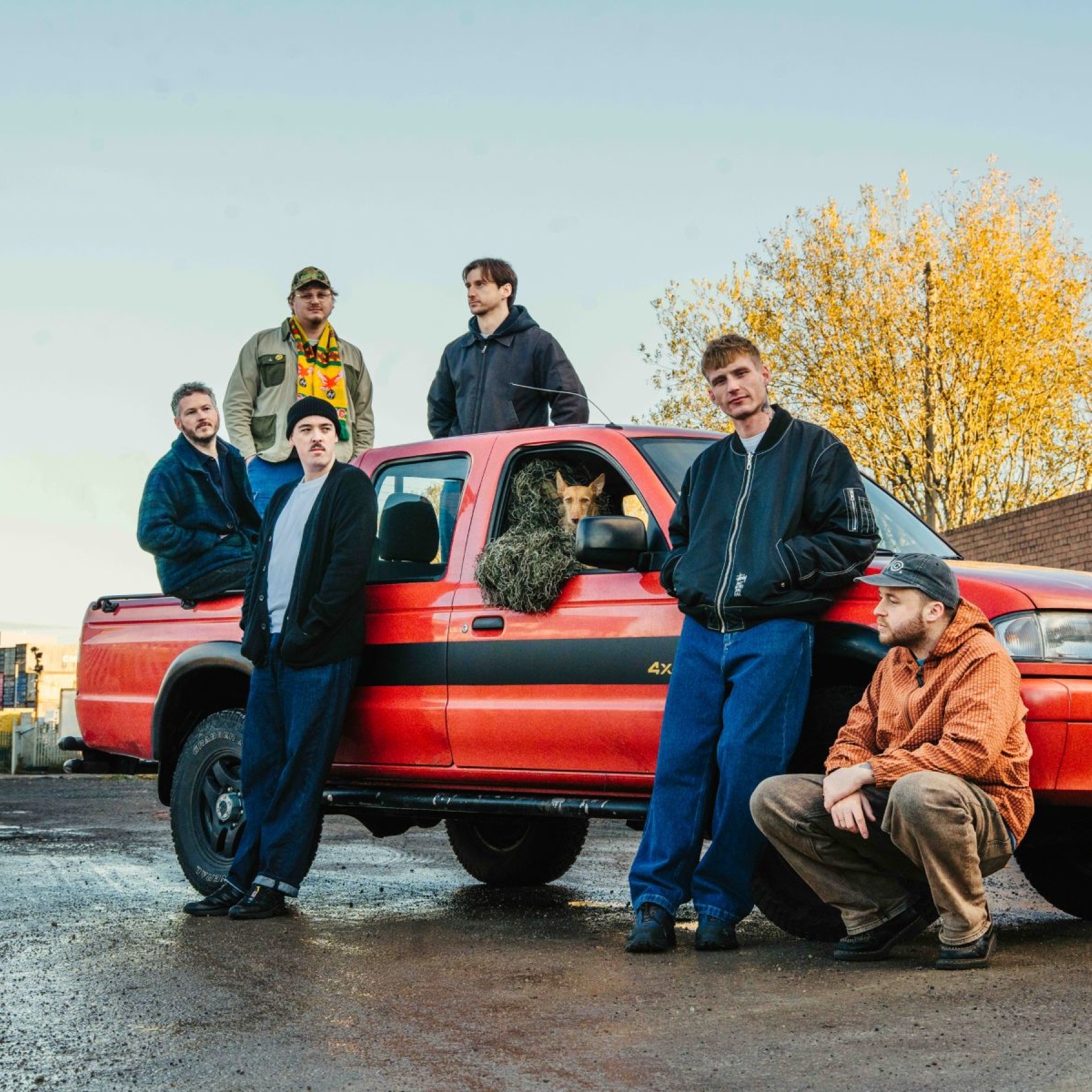 Group of men around and on a red car
