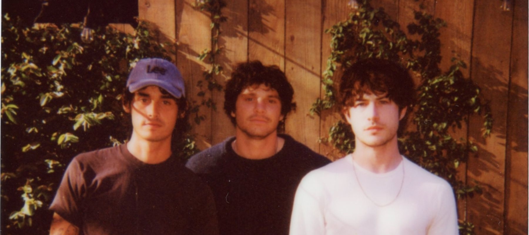 Three men standing in front of a fence