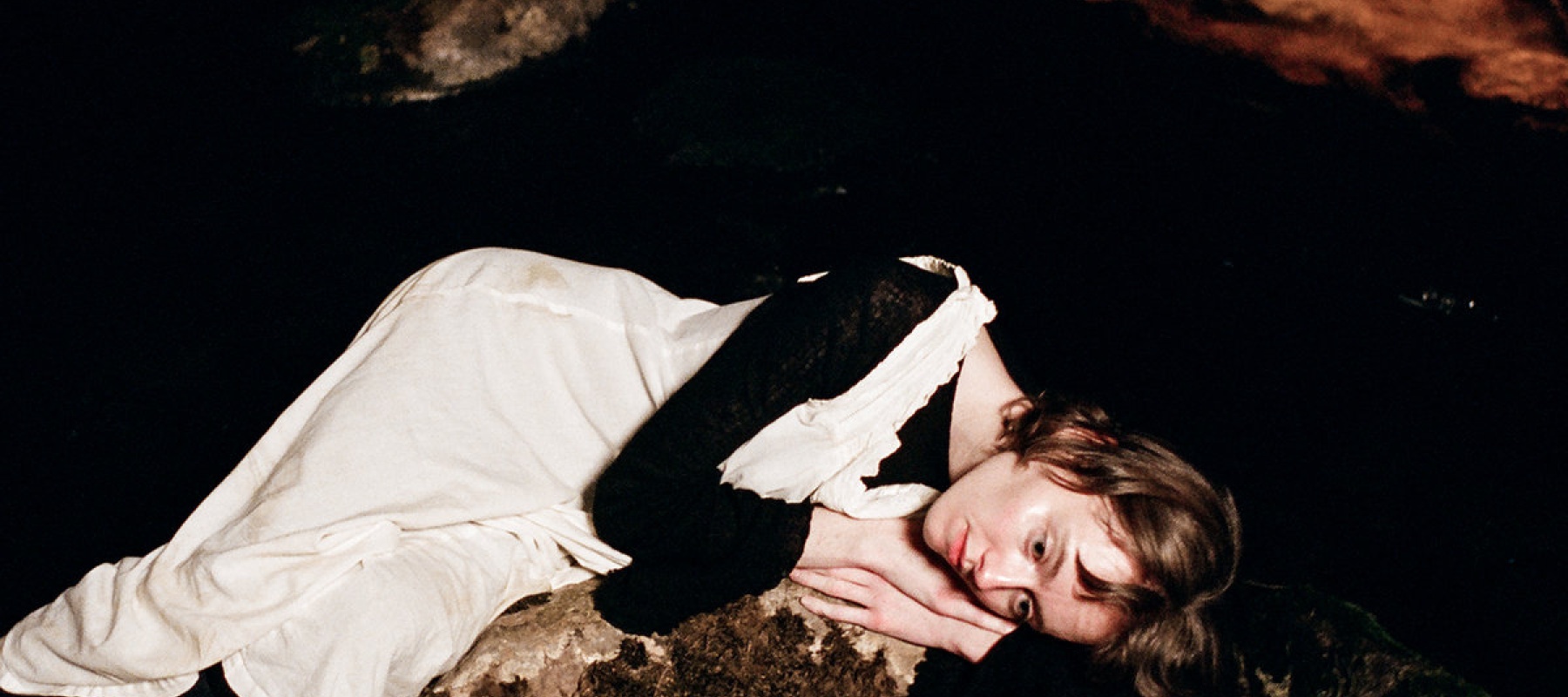 Woman lying on a stone on her side