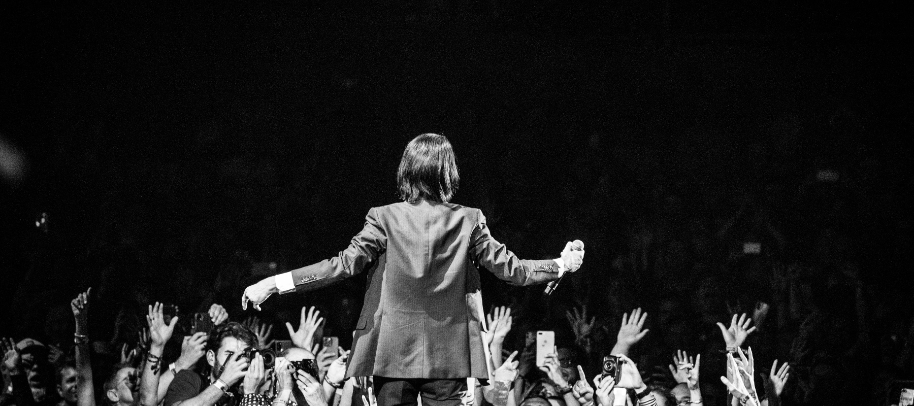 Man singing on stage, black and white within crowd