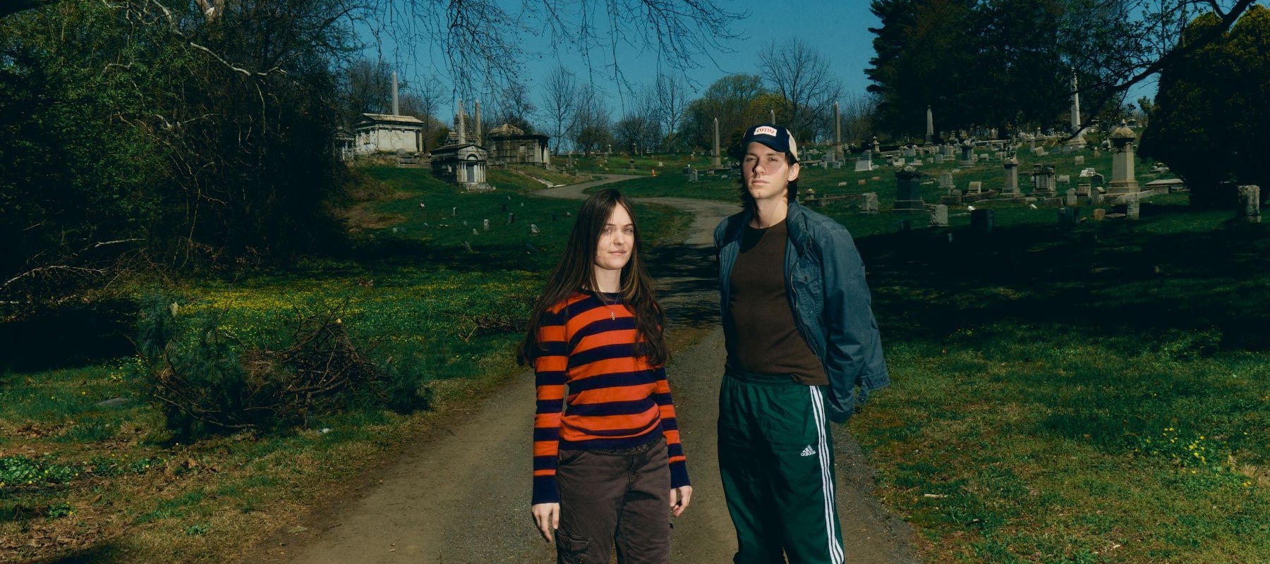 Two people standing in a sunny graveyard