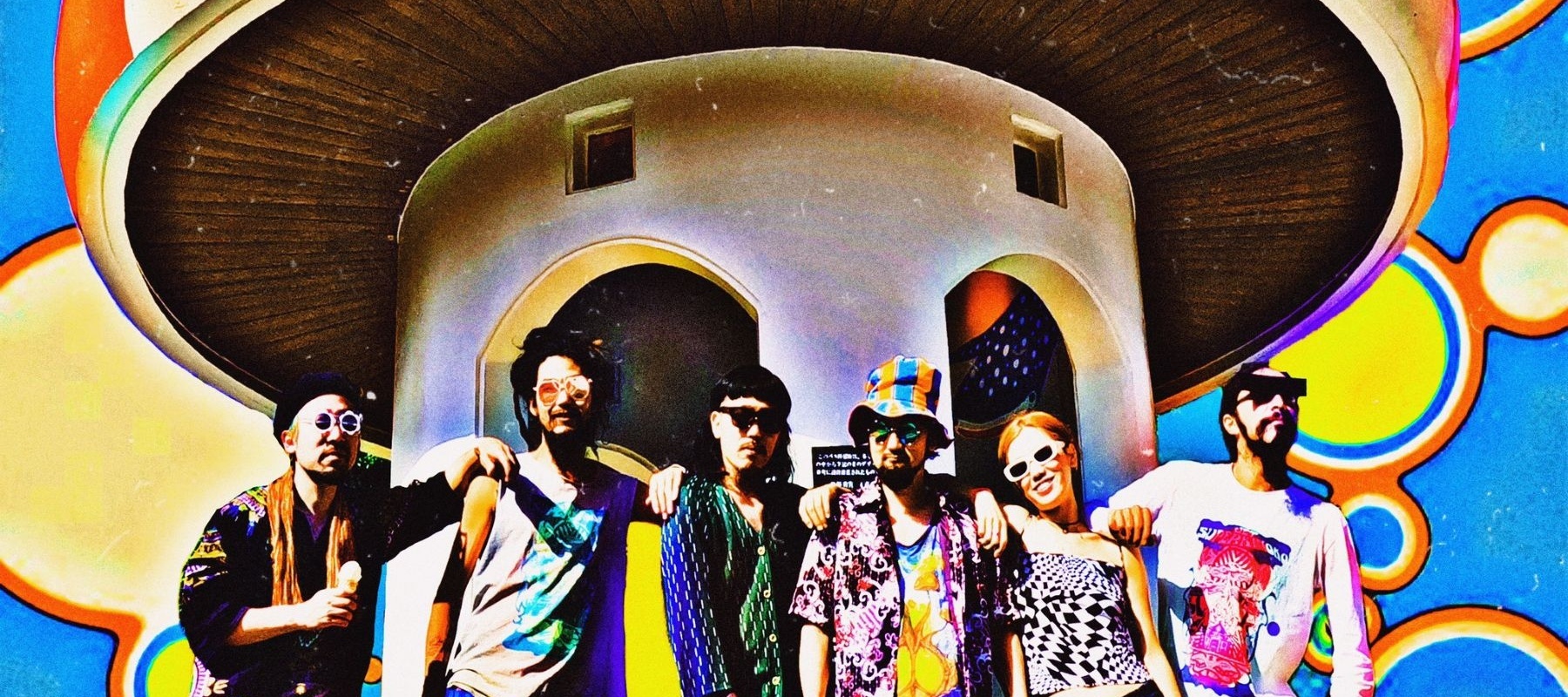Six people standing in fornt of a big mushroom-shaped house