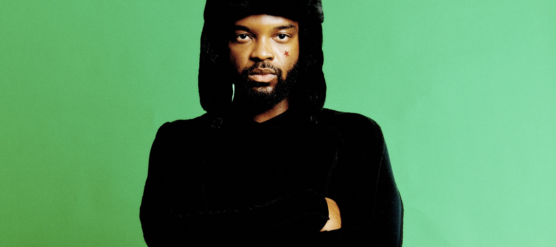 man standing in front of a green background, with a winter hat on