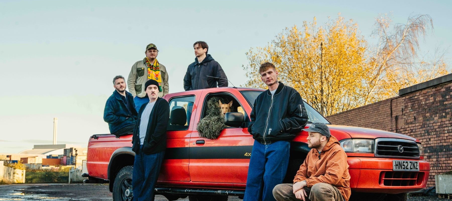 Group of men around and on a red car