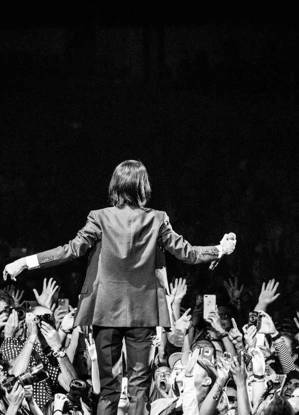 Man singing on stage, black and white within crowd
