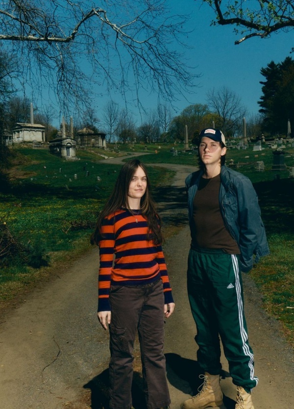 Two people standing in a sunny graveyard