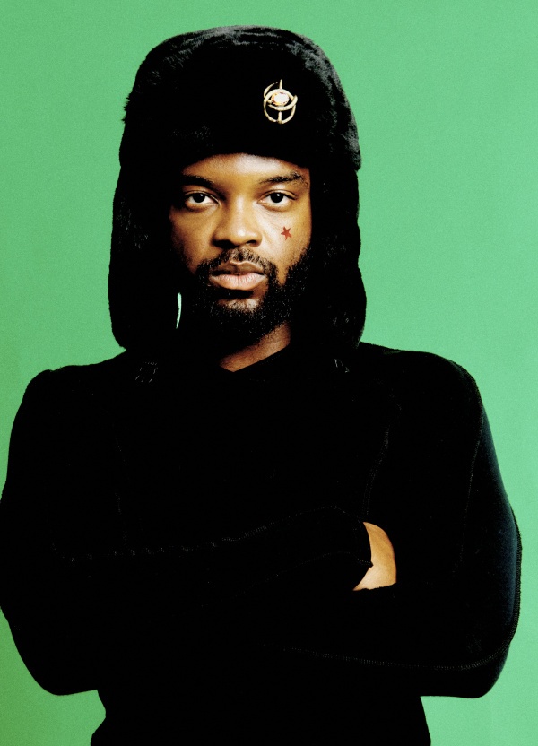 man standing in front of a green background, with a winter hat on